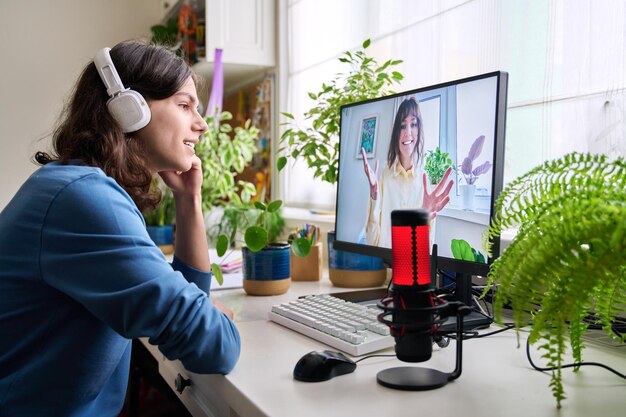 Online spotkanie nastolatków przyjaciół facet siedzący przy stole w domu rozmawiający uśmiechnięta kobieta na monitorze komputera przyjaźń technologia komunikacji młodzież styl życia młodzi ludzie koncepcja