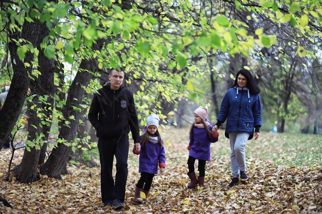 Opadanie liści w parku. Dzieci na spacer po jesiennym parku. Rodzina. Jesień. Szczęście.