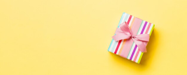Opakowany prezent świąteczny lub inny prezent świąt ręcznie wykonany w papierze z różową wstążką na żółtym tle