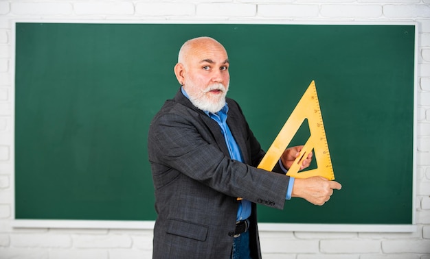 Opanuj kluczowe pojęcia powrót do szkoły matematyka i koncepcja ludzi Matematyka na tablicy ulubiony przedmiot starszy nauczyciel używa narzędzia trójkąta matematycznego brodaty nauczyciel mężczyzna przy tablicy