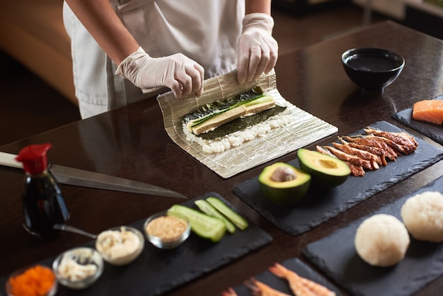 Zdjęcie opanuj robienie rolki sushi z nori, ryżem, ogórkiem i omletem przy użyciu maty bambusowej