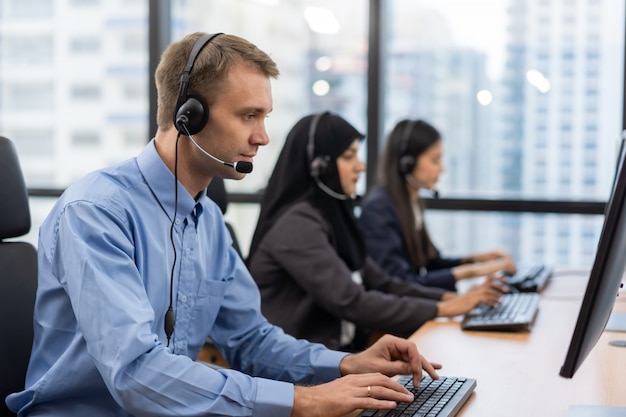 Operator biura obsługi klienta z zestawami słuchawkowymi pracującymi na komputerze w call center