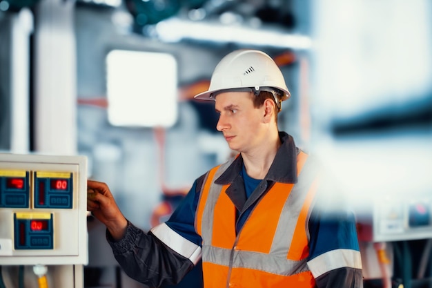 Operator lub inżynier w kasku i kamizelce ochronnej sprawdza nowoczesny sprzęt w zakładzie przemysłowym