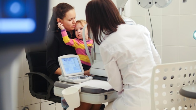 Zdjęcie opieka nad dziećmi - optometrysta w przychodni sprawdzający wzrok małego dziecka, teleobiektyw