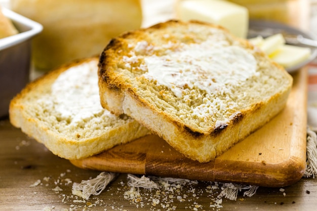 Opiekane kromki świeżo upieczonego chleba na zakwasie z masłem.