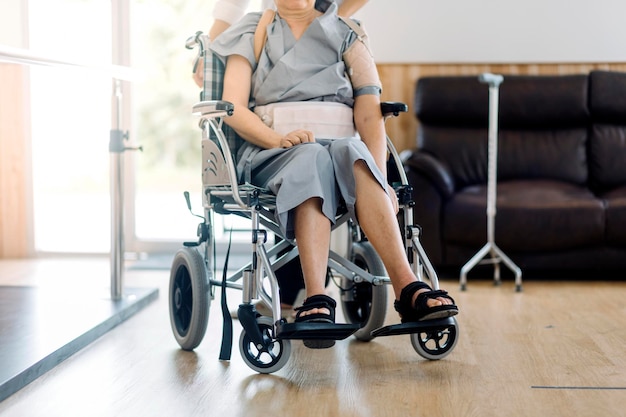 Opiekun lekarza lub pielęgniarki z starszym mężczyzną na wózku inwalidzkim w maskach ochronnych w domu lub domu opieki