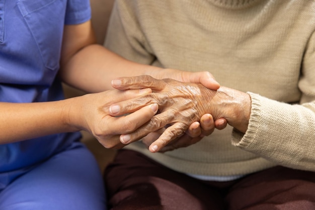 Opiekun masujący palec starszej kobiety w bolesnej opuchniętej dnie moczanowej