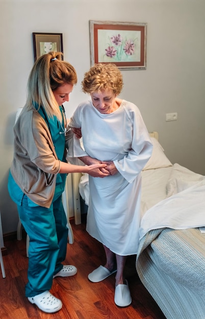Opiekunka pomagająca starszej pacjentce wstać