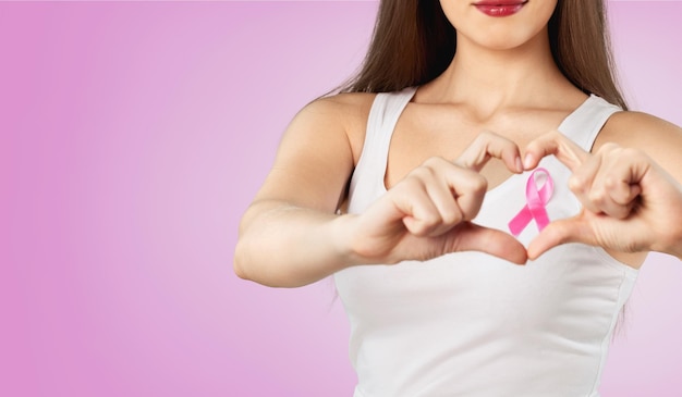 Oprawa serca z palców na piersi kobiety z różową plakietką wspierającą przyczynę raka piersi,