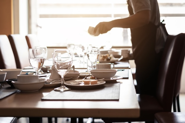 Opróżnia brudnych szkła i talerze na łomotanie stole w restauraci