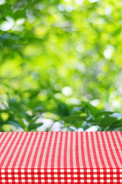 Opróżnia stół z czerwonym tablecloth nad plamy ogródem i bokeh tłem