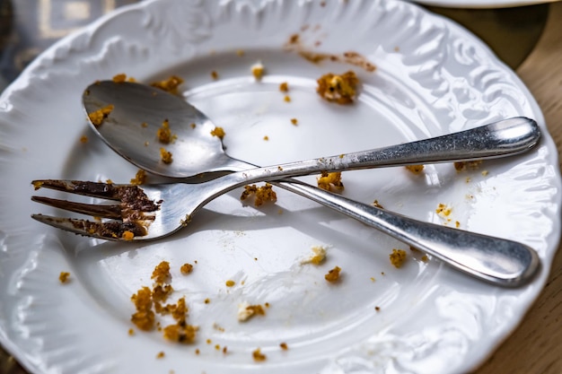 Opróżnij brudny talerz z łyżką i widelcem na stole po śniadaniu