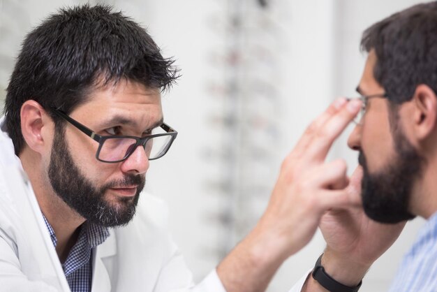 Zdjęcie optometryk badającego człowieka przy użyciu sprzętu do badania wzroku