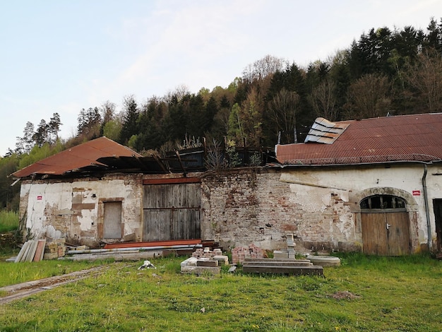 Zdjęcie opuszczony dom na polu obok drzew na tle nieba