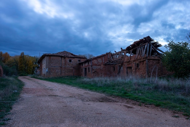 Zdjęcie opuszczony dom na polu przy drodze przeciwko niebu