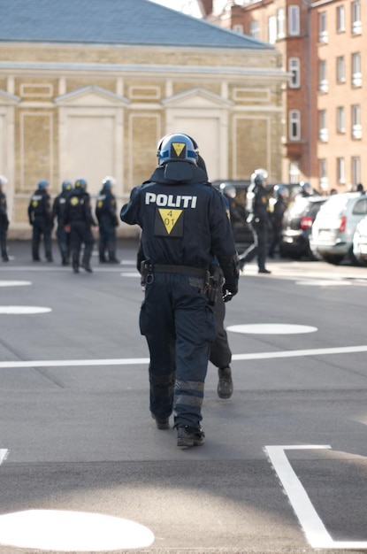 Zdjęcie organ bezpieczeństwa i tył funkcjonariusza policji w mieście pracującego w celu patrolowania protestu lub marszu służba publiczna organów ścigania i ochroniarz w mundurze dla ochrony na miejskiej ulicy miasta