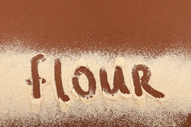 Zdjęcie organiczna mąka teff rozrzucona na brązowej powierzchni modny napis superfood mąka element projektu