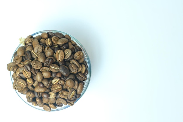 Organiczne brązowe palone ziarna kawy arabica w szklanej misce na białym tle. Skoncentruj się na ziarnach kawy