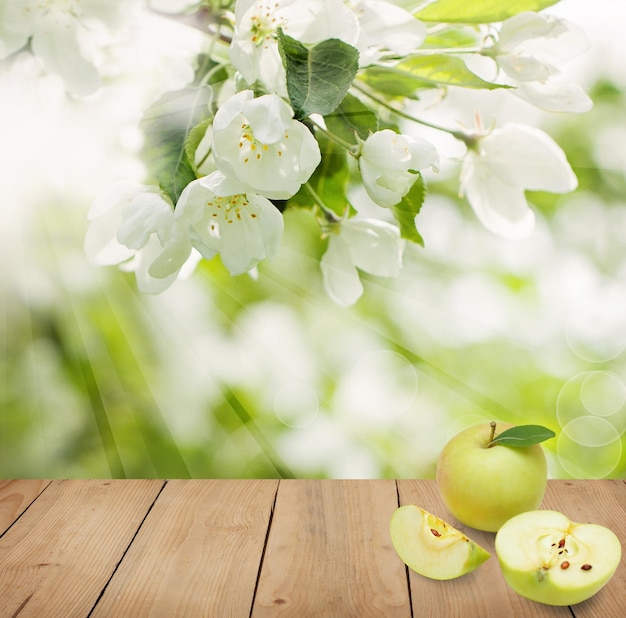 Organiczne tło żywności z zielonymi owocami jabłek, liśćmi, kwiatami i rustykalną drewnianą deską z miejscem na kopię