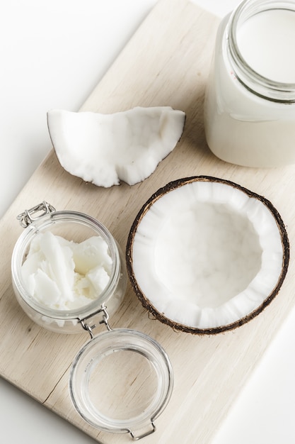 Organiczne zdrowe masło kokosowe i świeże kawałki kokosa na desce