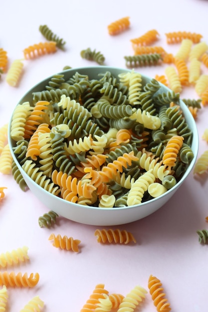 Organiczny fusilli tricolore rozlewający się na różowym tle