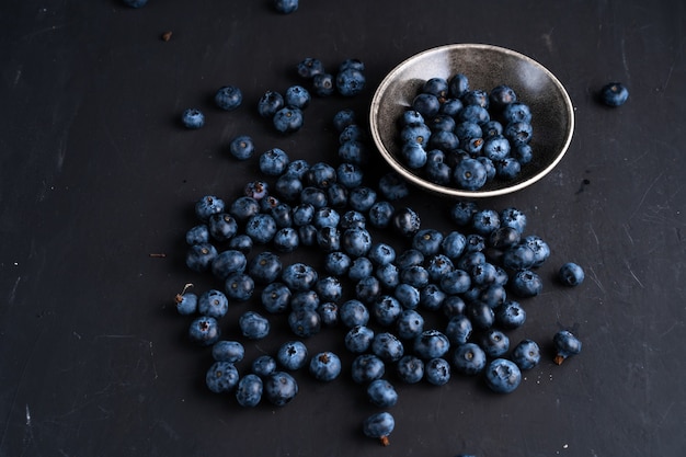 Organiczny pożywienie z borówkami, przeciwutleniacz, w koncepcji ceramicznej miski dla zdrowego odżywiania i odżywiania. Widok z góry na ciemnoczarną powierzchnię