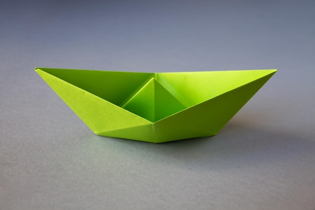 Origami z zielonej księgi łodzi na szarym tle