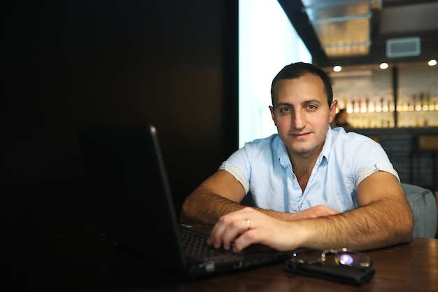 Ormiański przystojny mężczyzna pracujący za laptopem w kawiarni