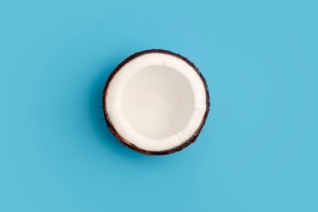 Orzechy kokosowe na niebieskim tle izolowania. Minimalna koncepcja kokosowego.