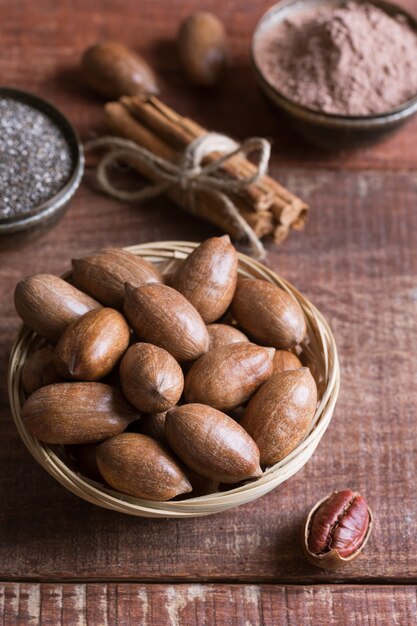 Orzechy pekan, nasiona chia i kakao w miskach na drewnianym stole