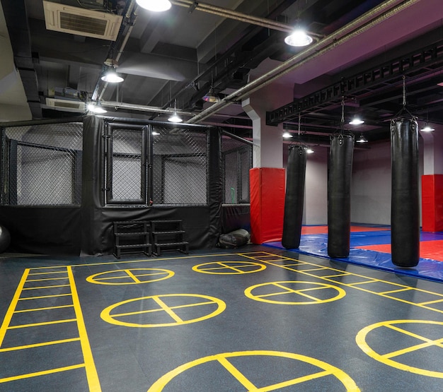 Ośmiokątna klatka do kickboxingu z workami bokserskimi w kompleksie sportowym