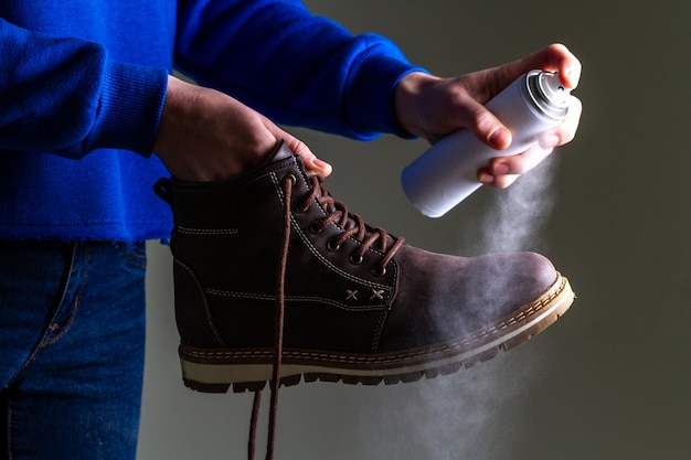 Zdjęcie osoba czyści i spryskuje zamszowe męskie buty codzienne w celu ochrony przed wilgocią i brudem. czyszczenie butów