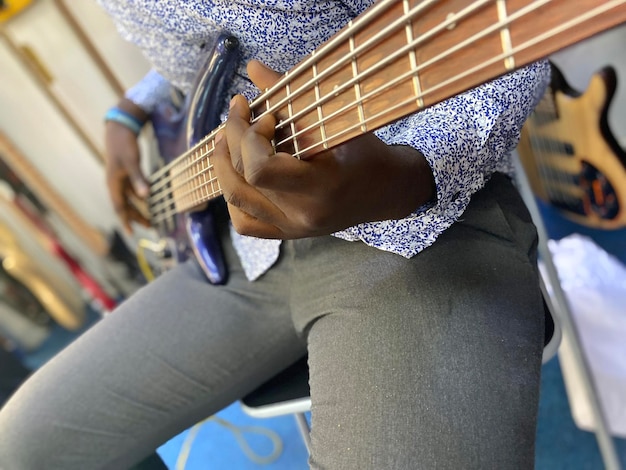Osoba grająca na gitarze basowej z niebieskim tłem.