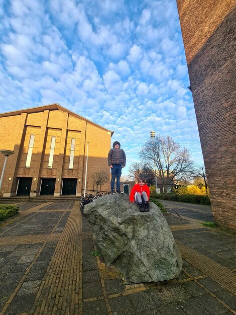 Osoba idąca ulicą z dużym kamieniem przed sobą