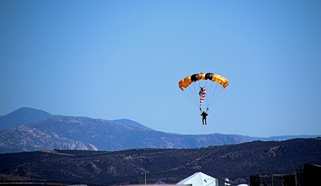 Zdjęcie osoba latająca paralotnią na jasnym niebieskim niebie