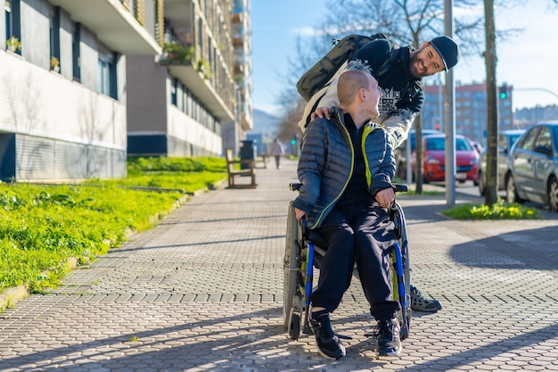 Zdjęcie osoba niepełnosprawna na wózku inwalidzkim spacerująca z przyjacielem na krześle na ulicy zimą