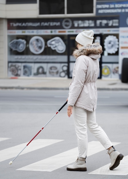 Zdjęcie osoba niewidoma idąca przez miasto ze ślepym kijem