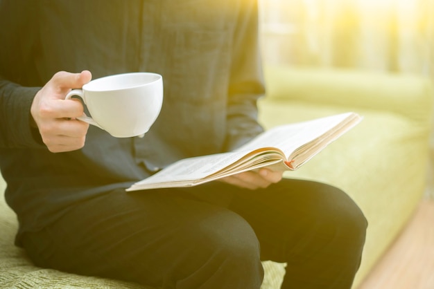 Osoba odpoczywająca w domu, czytająca książkę i pijąca herbatę, odpoczywająca wieczorem