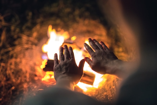 Osoba ostrzegająca ręce przy ognisku. wieczorna pora nocna