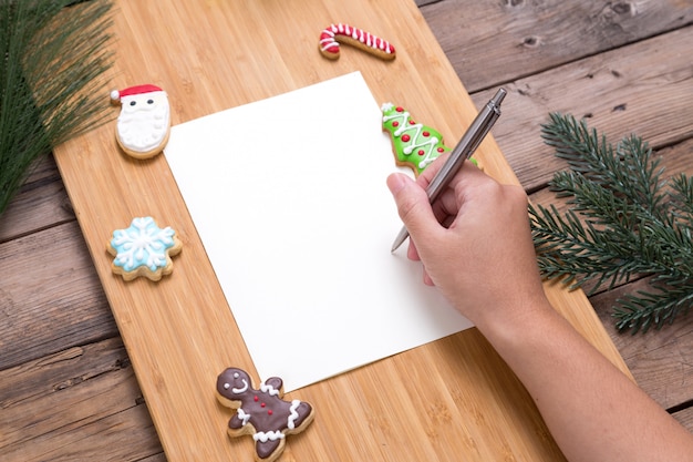 Osoba pisze na kartki świąteczne z domowych ciasteczek