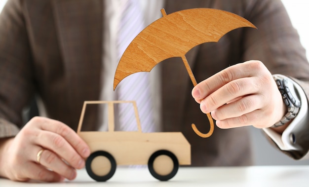 Zdjęcie osoba trzyma drewniany parasol nad samochodem