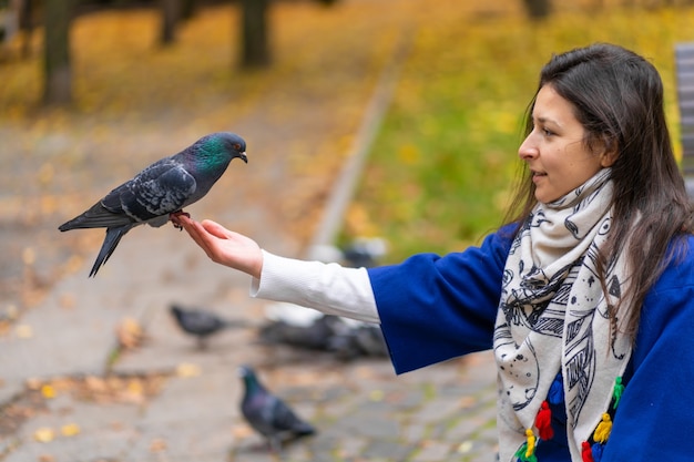 Zdjęcie osoba trzyma w ręku gołębicę. karmi gołębie w parku. oswój gołębia.