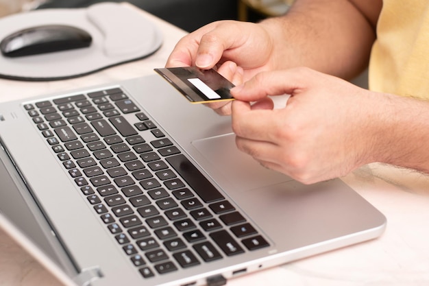 Osoba trzymająca kartę kredytową dwiema rękami z przodu laptopa e-commerce i koncepcja zakupów online
