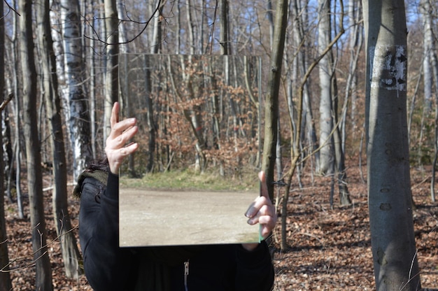 Zdjęcie osoba trzymająca lustro stojąca w lesie