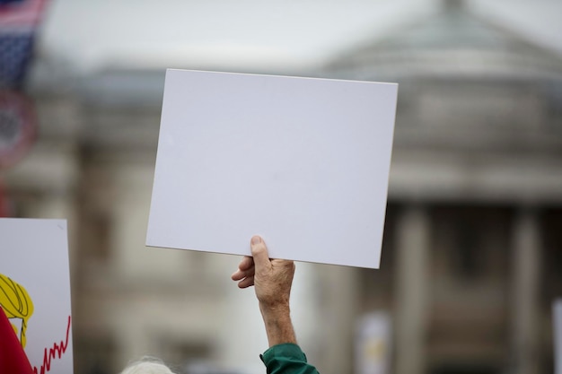 Osoba trzymająca pusty transparent protestacyjny na wiecu politycznym