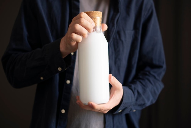 Osoba trzymająca szklaną butelkę z wegańskim mlekiem