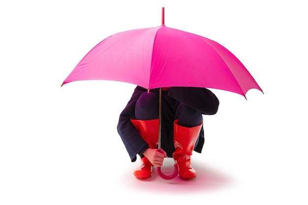 Zdjęcie osoba ubrana w czerwone gumowe buty i deszcz parasol na białym tle.