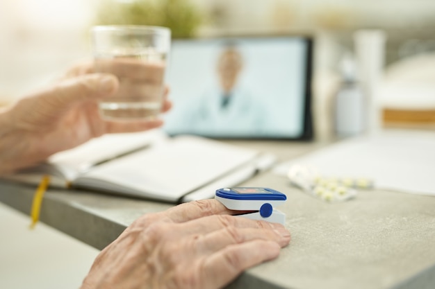 Osoba w podeszłym wieku biorąca swoje funkcje życiowe do konsultacji lekarskiej online