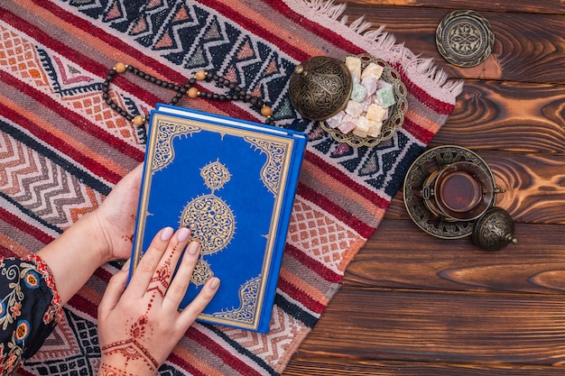 Zdjęcie osoba z mehndi trzymająca koran w pobliżu tureckiej rozkoszy
