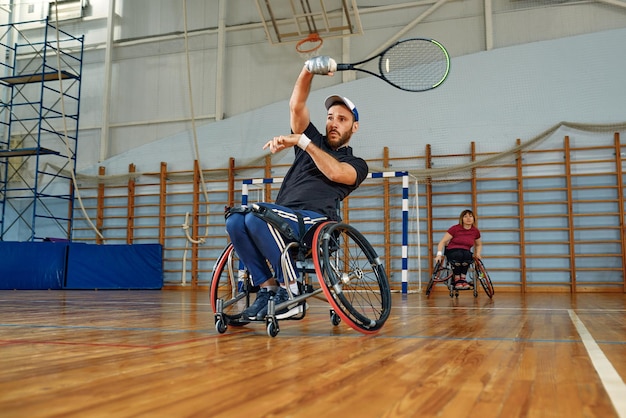 Osoby na wózku inwalidzkim grają w tenisa na korcie Tenis na wózkach inwalidzkich dla niepełnosprawnych
